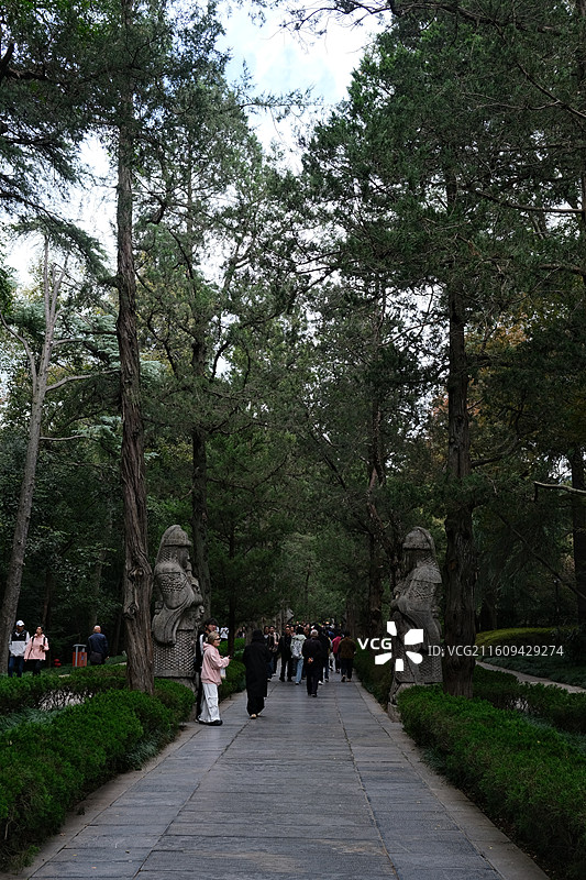 中式园林景致摄影素材 石板小径笔直延伸绿草两尊石兽雕像 浓密绿荫背景传统服饰人物 宁静悠远古朴园林风图片素材