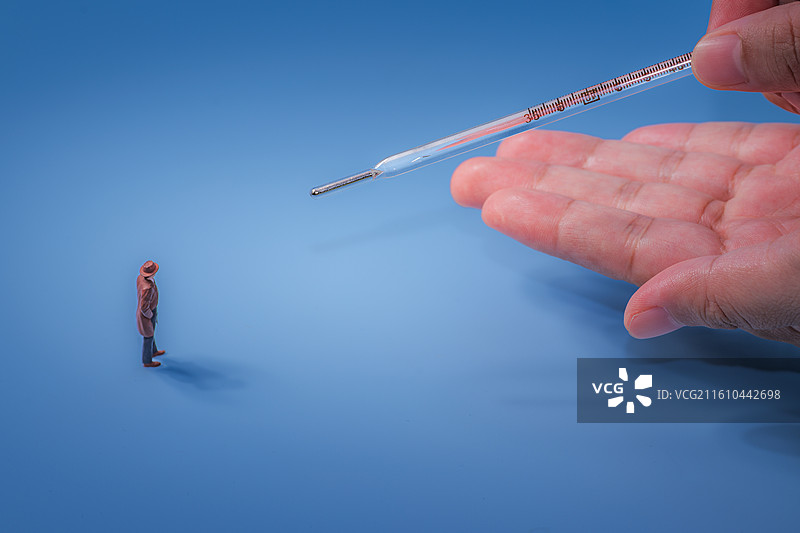 蓝色背景下医疗用品水银体温计和模型小人的特写镜头图片素材