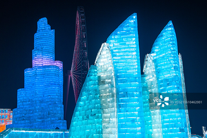 中国黑龙江哈尔滨冰雪大世界游乐场夜景 阿联酋哈利法塔和巴林世界贸易中心冰雕建筑彩色灯光和摩天轮图片素材