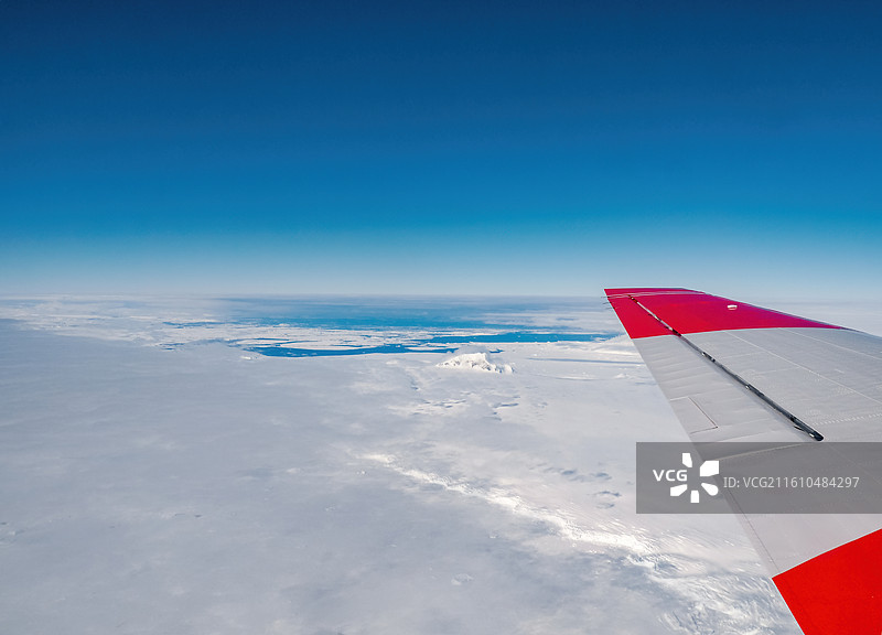 乘坐飞机飞越南极，机翼下是南极半岛海岸的冰川、海冰和大海图片素材