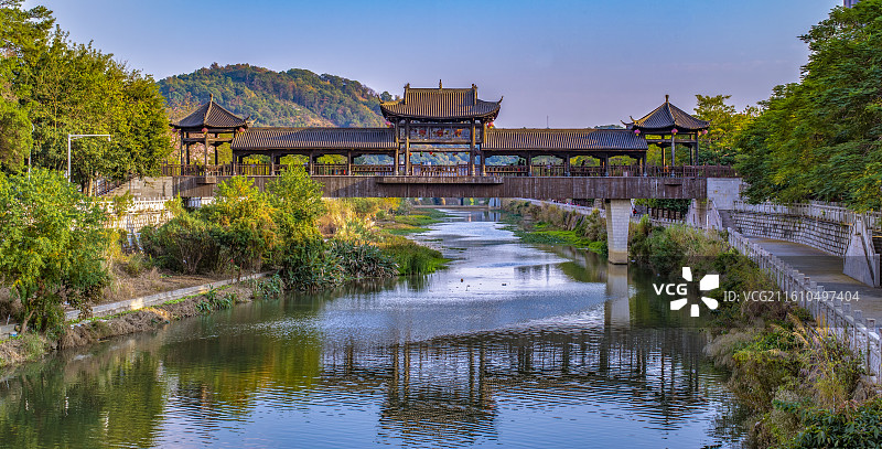 蓝天下福建省昙石山遗址博物馆绿林环绕的中间牌坊式硬山顶周空亭左右六柱五角凉亭的长廊桥图片素材