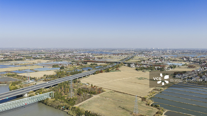 城市郊外高速公路航拍，田野与住宅区交织图片素材