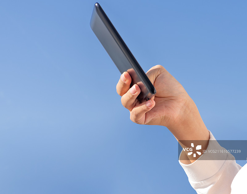 户外蓝天背景下，脑瘫患者手持墨水屏电子书进行无障碍阅读，展示残障人士的科技生活与希望。图片素材