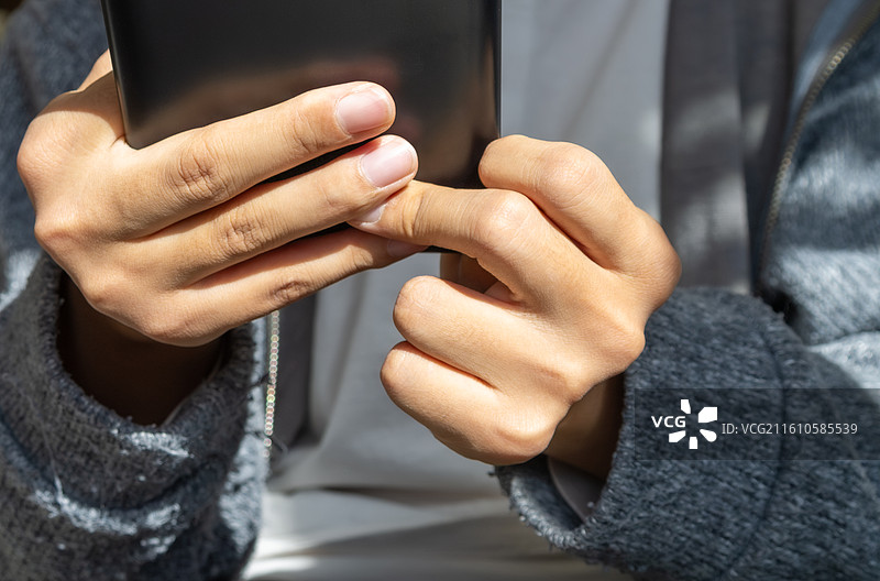 脑瘫患者手部用力抓握电子设备的医学细节特写，真实呈现肌肉张力与神经系统康复特征。图片素材