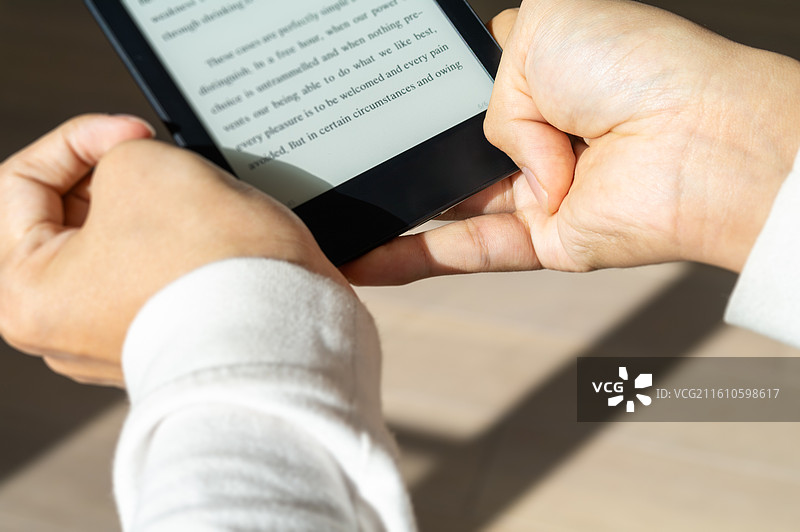 居家办公场景中，身穿白衣的残障人士专注于操作墨水屏平板，体现终身学习与自我教育的正能量。图片素材