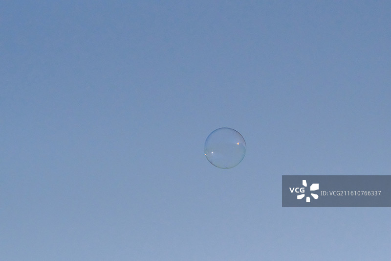 蓝色天空中飘扬的七彩肥皂泡泡。高楼建筑白鸽背景图壁纸图片素材