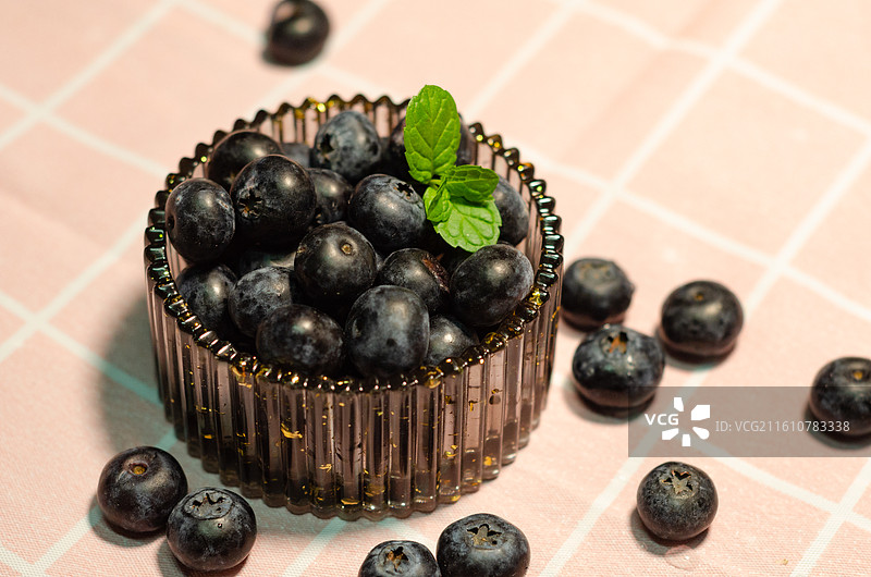 盛放着蓝莓的容器旁散落着蓝莓图片素材