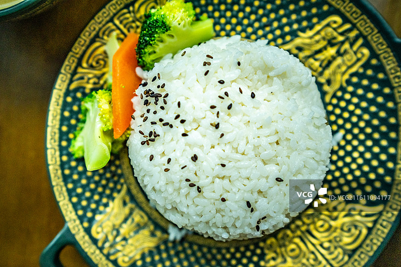 一盘有黑芝麻和蔬菜点缀的米饭图片素材