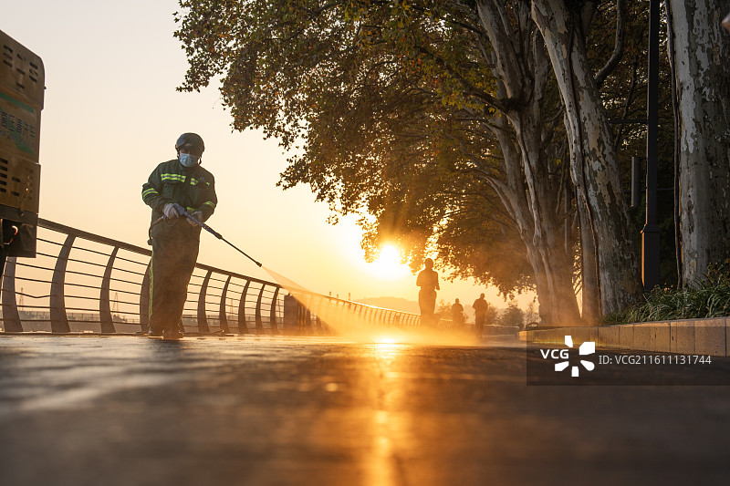 湖北武汉东湖边在清晨阳光里的环卫工人图片素材