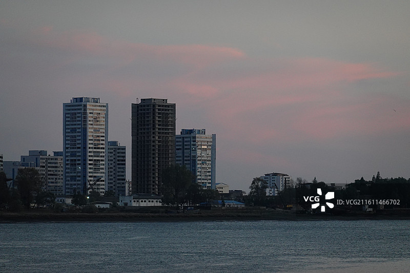 辽宁省丹东市振兴区鸭绿江断桥中朝友谊桥：远眺朝鲜新义州高楼大厦城市天际线晚霞暮光图片素材