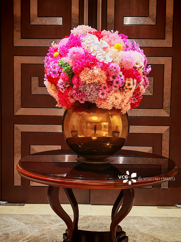 艳花团裹满金樽光 粉绯花簇挤成甜软的团，金樽瓶映着缠向瓣尖，连木纹桌都浸着憧憬这缕热闹的香，鲜活盛景图片素材