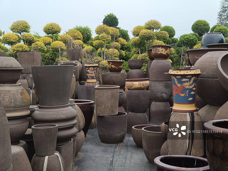 一堆陶瓷花盆和背景绿色植物图片素材