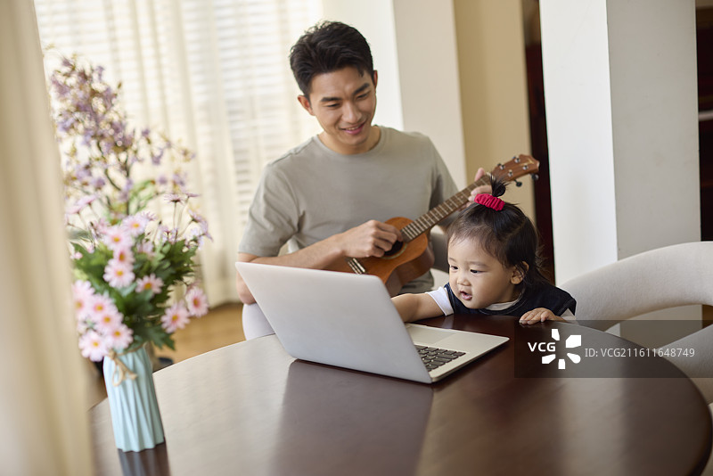 宝爸边带娃边弹尤克里里图片素材
