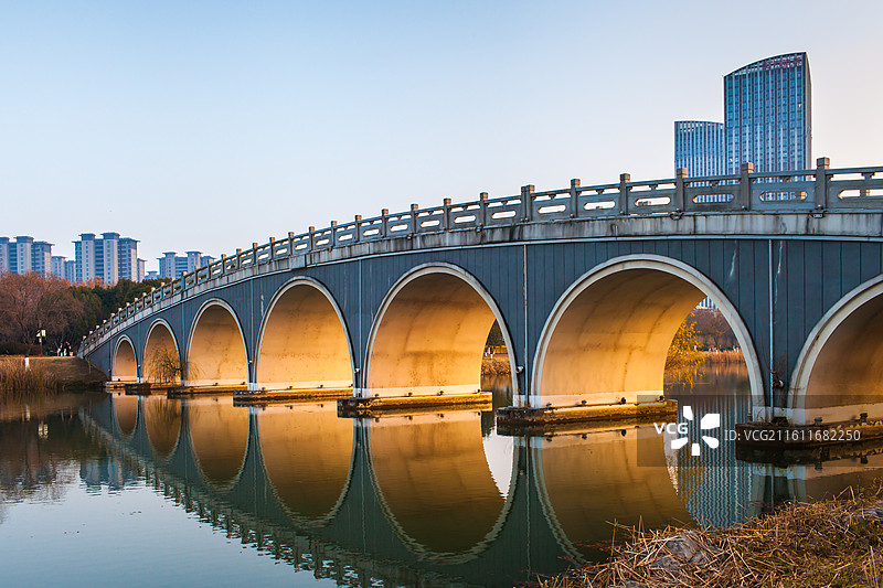 城市公园内金色阳光穿过桥孔图片素材