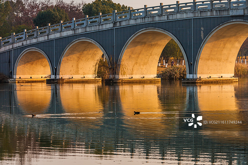 城市公园内金色阳光穿过桥孔图片素材