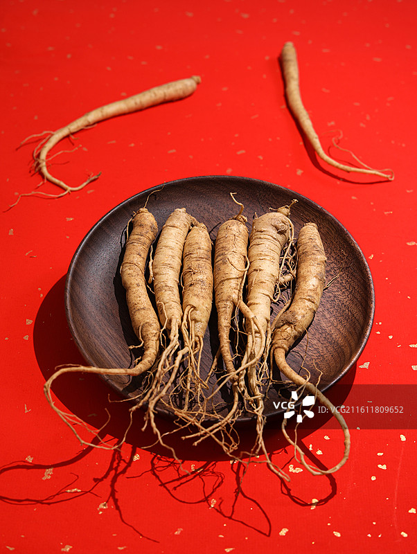 红色桌面上的传统中医中药材滋补营养品新鲜生人参图片素材