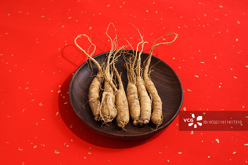 红色桌面上的传统中医中药材滋补营养品新鲜生人参图片素材