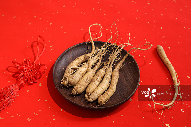 红色桌面上的传统中医中药材滋补营养品新鲜生人参图片素材