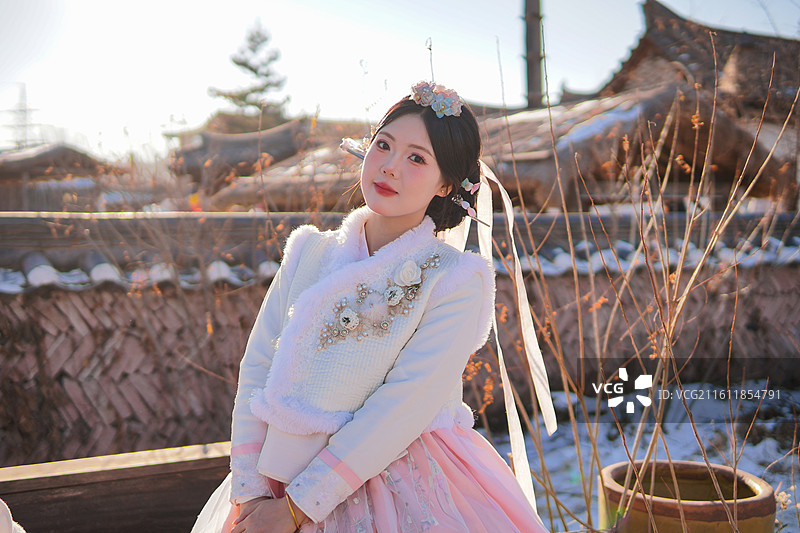 一个穿着朝鲜族服饰的女孩在延吉民俗园传统建筑前图片素材