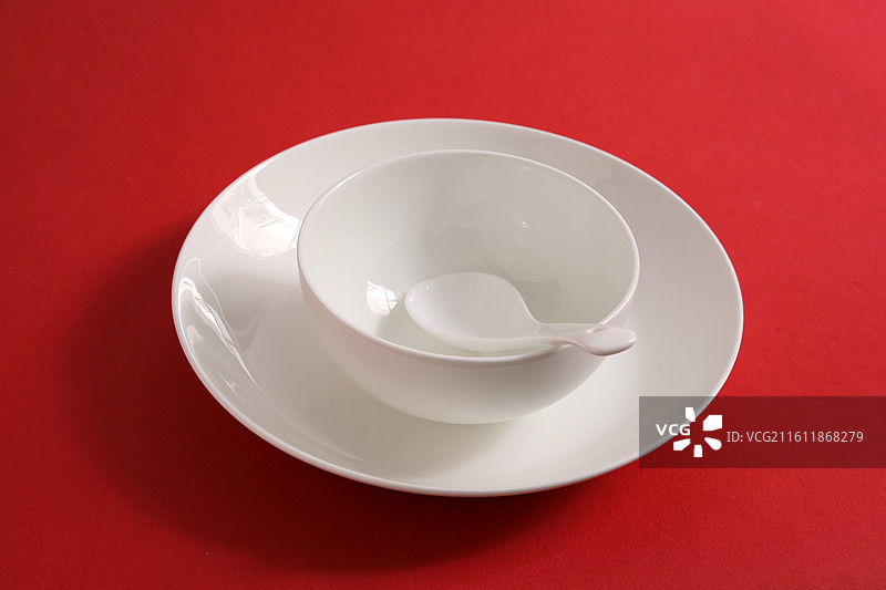 红色桌面上摆放着白色的餐具瓷器碗盘子碟子图片素材