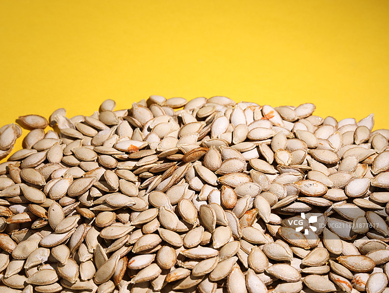 黄色桌面上摆放着的营养健康干货坚果美食南瓜子图片素材