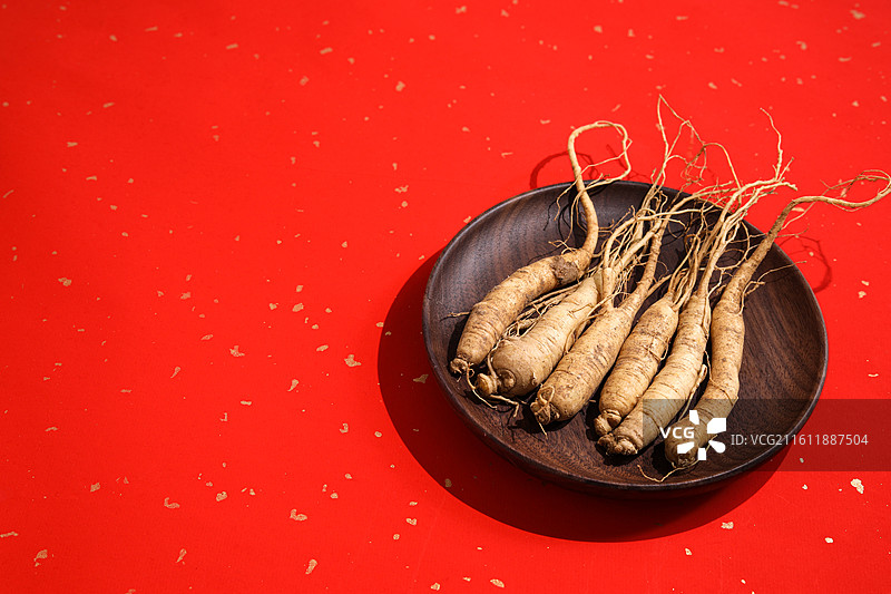 红色桌面上的传统中医中药材滋补营养品新鲜生人参图片素材