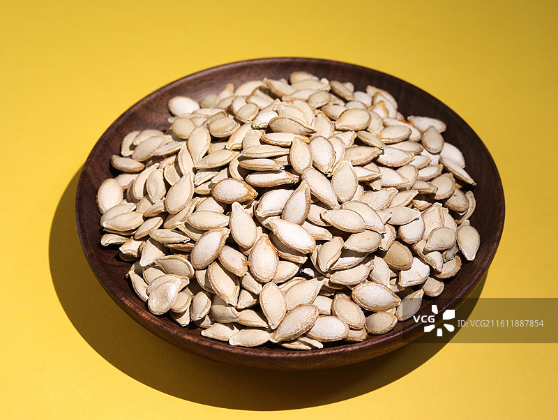 黄色桌面上摆放着的营养健康干货坚果美食南瓜子图片素材