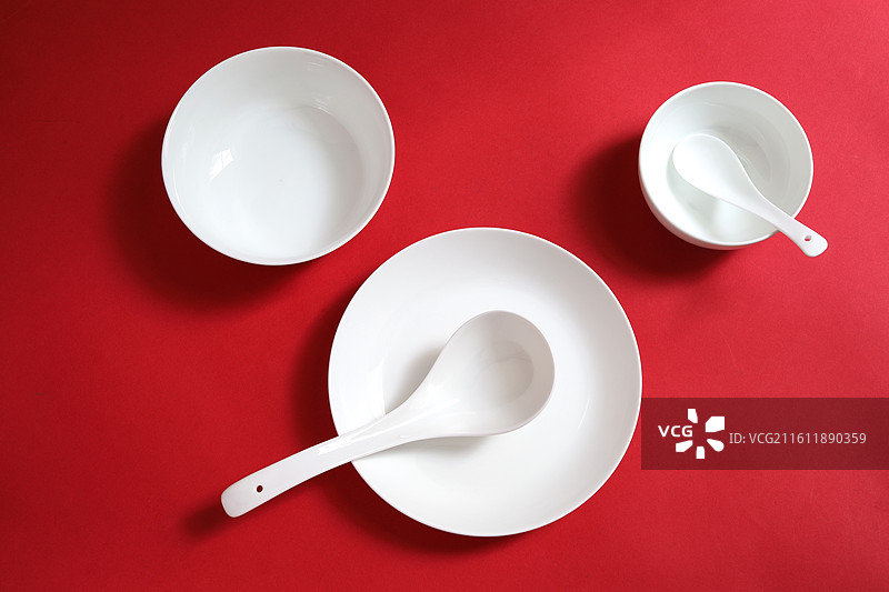 红色桌面上摆放着白色的餐具瓷器碗盘子碟子图片素材