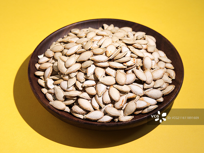 黄色桌面上摆放着的营养健康干货坚果美食南瓜子图片素材