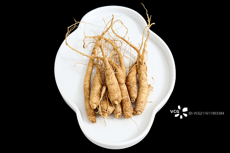 黑色背景盘子上的中国传统中医中药材滋补营养品新鲜生人参图片素材