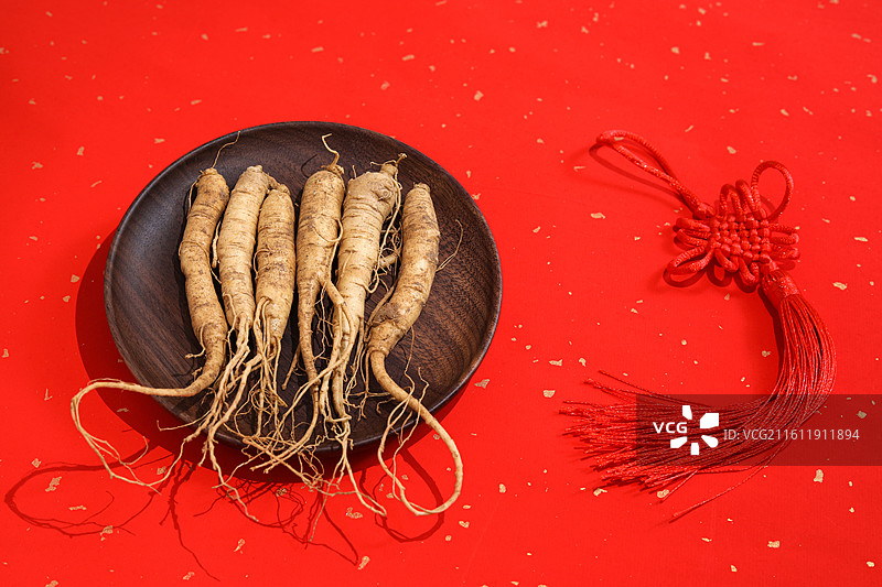 红色桌面上的传统中医中药材滋补营养品新鲜生人参图片素材