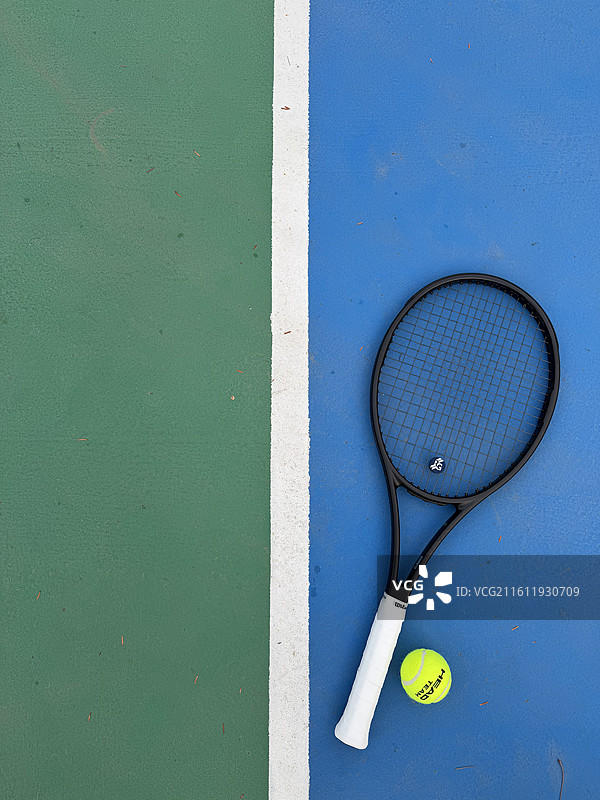 放在蓝绿相间网球场上的黑色网球拍的高角度视角图片素材