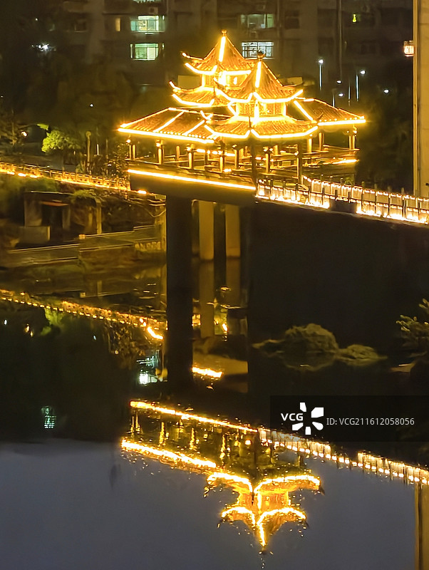 夜色里，中式亭阁立在江畔桥体上，暖灯勾勒轮廓，光影在水面形成绝美倒影，国风韵味十足。图片素材