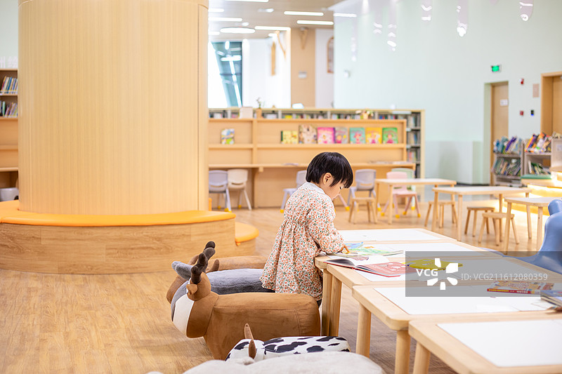一名中国小女孩在图书馆绘本区阅读图片素材