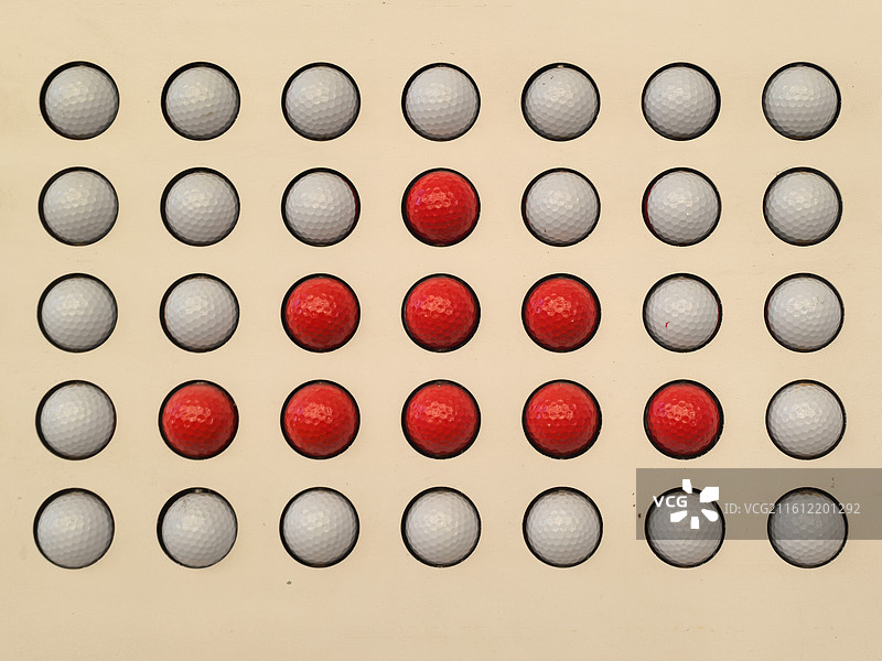 小区里一张长椅上，带可以滚动的红白两色按摩球，可以排列成很多图案。这张中间形成红色三角图片素材