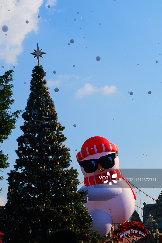 圣诞树，挂满金色和红色的球饰，背景是明亮的蓝天图片素材