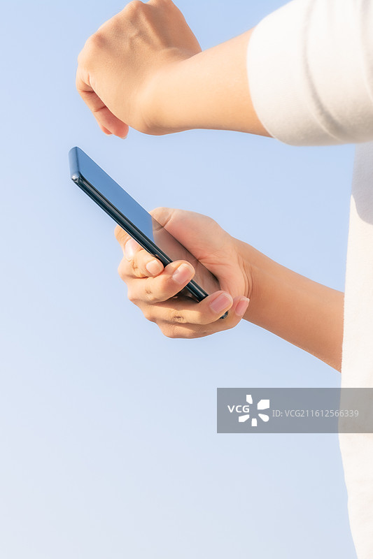 户外蓝天背景下脑瘫患者使用智能手机进行数字化通讯，展示科技无障碍生活与互联希望。图片素材