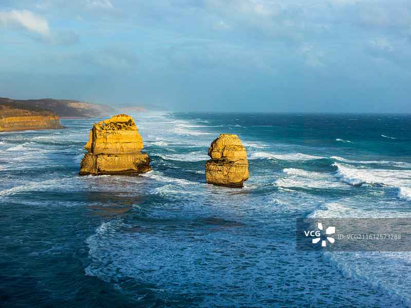 这张照片定格了澳大利亚大洋路标志性的12门徒景观。蔚蓝天空下，海浪汹涌拍打着古老的石灰岩柱。图片素材