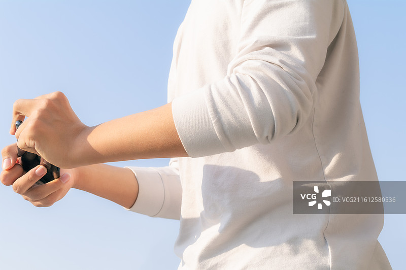 户外蓝天背景下脑瘫患者使用智能手机进行数字化通讯，展示科技无障碍生活与互联希望。图片素材