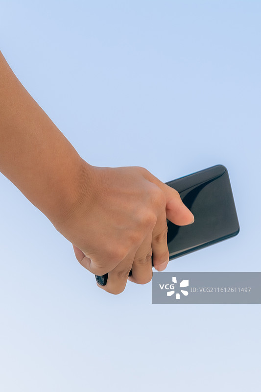 户外蓝天背景下脑瘫患者使用智能手机进行数字化通讯，展示科技无障碍生活与互联希望。图片素材