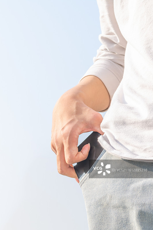 脑瘫患者在户外从牛仔裤兜取出智能手机，展示便捷的移动互联生活与科技无障碍。图片素材