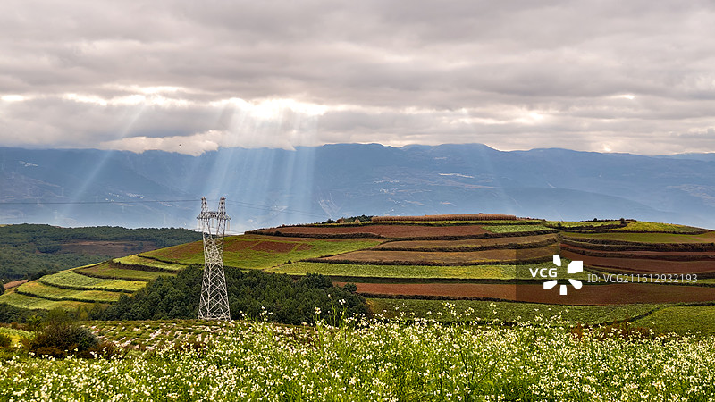 《天光织野》，拍摄于昆明东川红土地。天光穿透云层，如同丝线，将田野编织成一幅壮丽的大地锦缎。图片素材