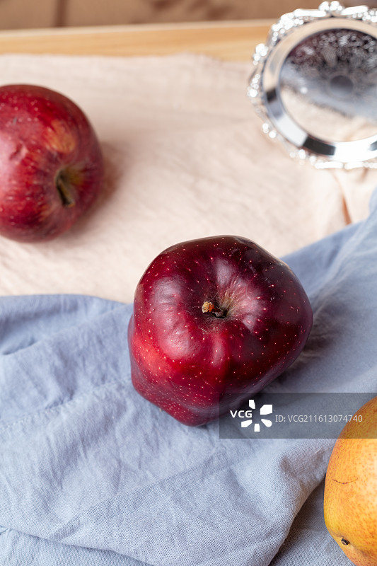 蓝布上摆放的新鲜花牛苹果图片素材
