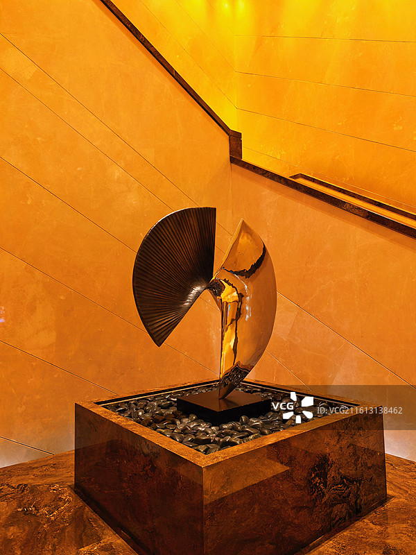 暖金灯光下，金属雕塑如艺术精灵，在石粒与大理石间跳着现代美学的舞图片素材