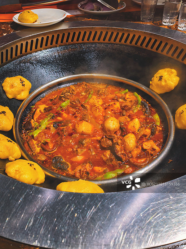 铁锅炖肉咕嘟冒泡，金黄贴饼围一圈，这烟火气直接把食欲拉满图片素材