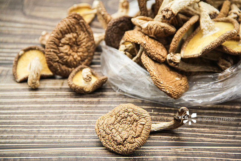 木制桌子背景下塑料袋里的香菇干货特写图片素材