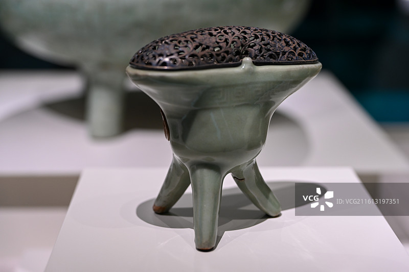 青瓷香炉，三足鼎立式造型搭配镂空雕花盖，釉色温润如玉，尽显中式古典雅韵，适用于传统文化、工艺美术等场图片素材