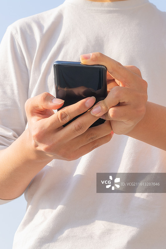 户外蓝天背景下脑瘫患者使用智能手机进行数字化通讯，展示肢体障碍人士的科技无障碍生活。图片素材