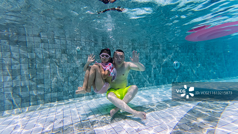 一对父女在游泳池里游泳图片素材
