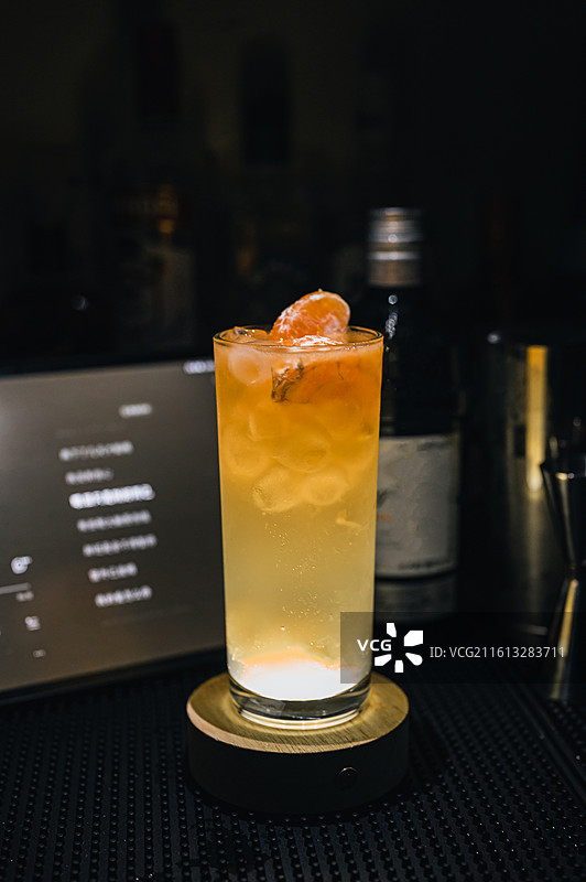 暗调酒吧发光底座上的柑橘点缀长饮鸡尾酒图片素材